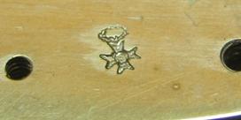 a stamp mark showing possibly a floral reef and a cross, found on the inside of the front plate